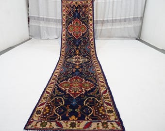May include: A long, narrow rug with a blue background and intricate floral patterns in shades of red, yellow, and cream. The rug has a fringe border.