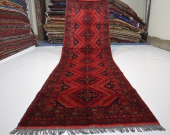 May include: A red, blue, and gold patterned runner rug with fringe. The rug has a geometric design with diamond shapes and floral motifs.
