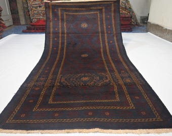 May include: A long, rectangular rug with a dark blue background and intricate patterns. The rug features a central medallion and borders in shades of brown and red. The design includes floral and geometric motifs, with a fringed edge.