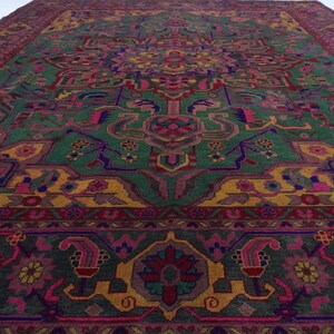 May include: A vintage rug with a colourful geometric pattern. The rug features shades of green, yellow, pink, and purple. The design is intricate and detailed, with a central medallion and repeating motifs.