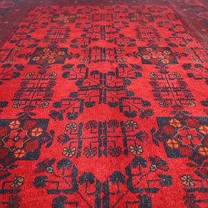May include: A red rug with a traditional Persian design featuring intricate floral patterns and geometric shapes in black and white.