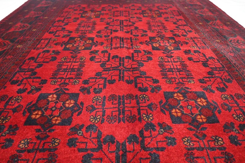 May include: A red rug with a traditional Persian design featuring intricate floral patterns and geometric shapes in black and white.