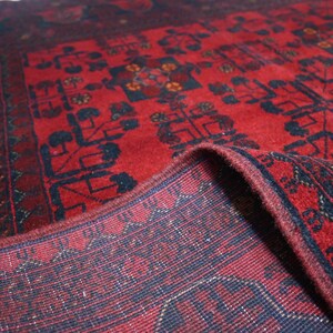 May include: A red and blue rug with a traditional Persian design. The rug is folded in half, showing the intricate details of the weave.