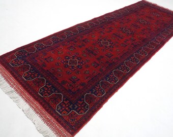 May include: A red and blue patterned runner rug with fringe on the ends. The rug has a traditional design with intricate details.
