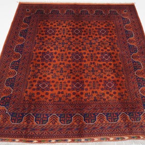 May include: A traditional Persian rug with a red background and intricate blue and white patterns. The rug has a fringed border and a central medallion.