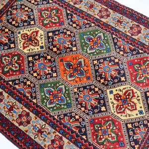 May include: A traditional Persian rug with a geometric pattern in shades of red, blue, green, and cream. The rug features a central medallion with intricate floral designs and a border with repeating motifs.