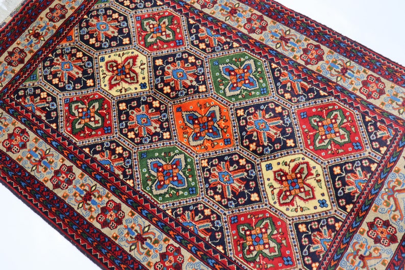 May include: A traditional Persian rug with a geometric pattern in shades of red, blue, green, and cream. The rug features a central medallion with intricate floral designs and a border with repeating motifs.