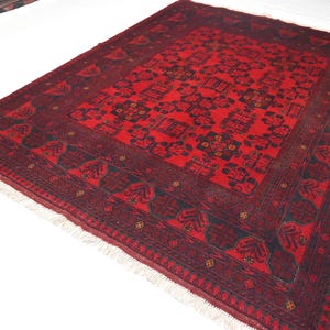 May include: A red and black patterned rug with a fringe border. The rug has a traditional design with intricate details.