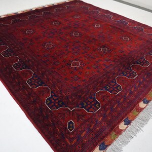 Pu&ograve; includere: Un tappeto rosso, blu e crema con un motivo geometrico e frange. Il tappeto ha un design tradizionale con dettagli intricati.
