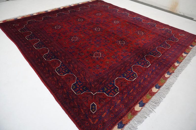 Pu&ograve; includere: Un tappeto rosso, blu e crema con un motivo geometrico e frange. Il tappeto ha un design tradizionale con dettagli intricati.