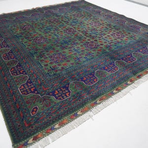 May include: A green, blue, and red patterned rug with a fringe border. The rug has a traditional design with intricate details.