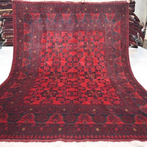 May include: A red and black hand-woven rug with a traditional Persian design. The rug has a central medallion and a border with intricate patterns.
