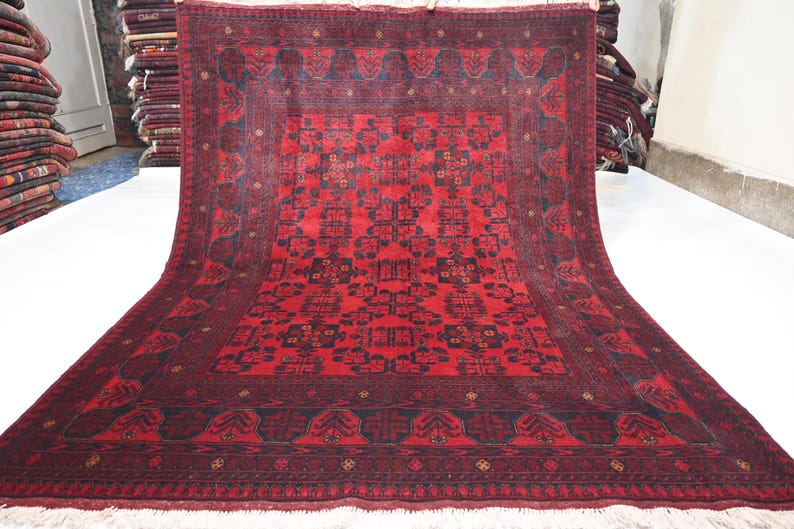 May include: A red and black hand-woven rug with a traditional Persian design. The rug has a central medallion and a border with intricate patterns.