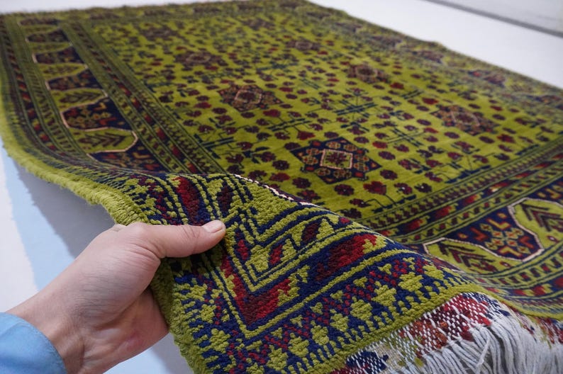 May include: A green, red, and blue patterned rug with fringe. The rug has a geometric design and is folded in half.