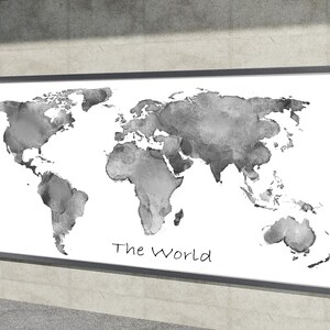 Könnte beinhalten: Eine gerahmte Aquarell-Weltkarte in Grautönen, montiert auf weißem Hintergrund. Die Kontinente sind mit einem weichen, verschwommenen Effekt dargestellt. Die Worte "The World" sind in einer handschriftlichen Schriftart am unteren Rand der Karte geschrieben.