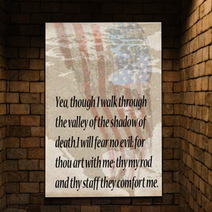 Könnte beinhalten: Ein rechteckiger Druck mit einem verblassten Design der amerikanischen Flagge im Hintergrund. Der Druck zeigt ein Zitat aus Psalm 23,4 in schwarzem Text: „Ja, wenn ich auch wanderte durch das Tal des Todesschattens, fürchte ich kein Unglück; denn du bist bei mir, dein Stecken und dein Stab trösten mich."