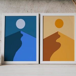 Könnte beinhalten: Zwei gerahmte abstrakte Kunstdrucke. Einer zeigt eine blaue und marinefarbene Berglandschaft mit einem weißen Mond. Der andere hat eine braune und gelbe Berglandschaft mit einer orangefarbenen Sonne. Beide sind in weißen Rahmen.