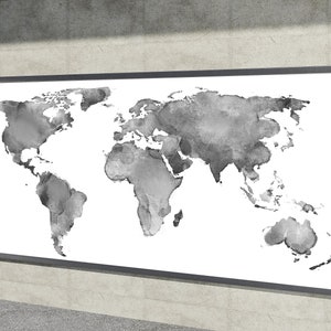 Könnte beinhalten: Ein gerahmter Kunstdruck einer Weltkarte. Die Karte ist in Grautönen in Aquarelltechnik auf weißem Hintergrund dargestellt. Der Rahmen ist dunkelgrau. Das Kunstwerk wird an einer Betonwand ausgestellt.