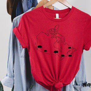 May include: Red t-shirt with a black outline of Canada and black bears in different provinces. The text "Neapolitan Primary" is on the bottom right corner of the shirt.