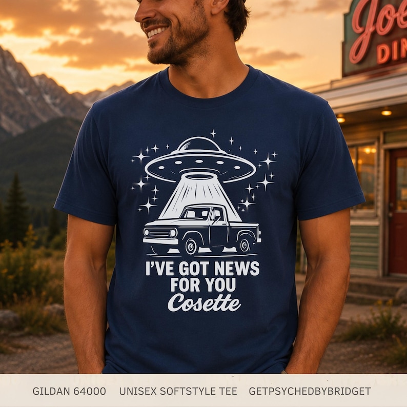 May include: A navy blue short-sleeve t-shirt featuring a white graphic of a pickup truck being abducted by a UFO, surrounded by stars. The text reads I'VE GOT NEWS FOR YOU Cosette. The shirt is a Gildan 64000 unisex softstyle tee.