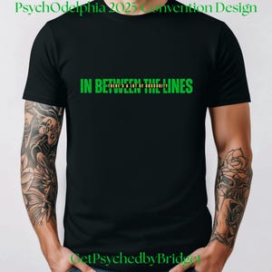 May include: Black t-shirt with green text that reads "In Between The Lines There's A Lot Of Obscurity".
