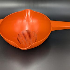May include: Orange plastic colander with a handle and a strainer.