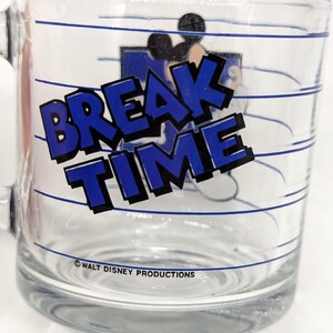 May include: Clear glass mug with the words "BREAK TIME" in blue block letters. The mug features a cartoon image of Mickey Mouse and blue horizontal lines. The text "WALT DISNEY PRODUCTIONS" is printed at the bottom.