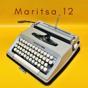 Peut inclure: Une machine à écrire Maritsa 12 vintage de couleur gris clair, avec des touches blanches et une base noire. L'image est sur un fond jaune vif. Le texte "Maritsa 12" est affiché en rouge en haut.