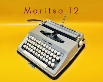 May include: A vintage Maritsa 12 typewriter in a light gray color, with white keys and a black base. The image is set against a bright yellow background. The text "Maritsa 12" is displayed in red at the top.