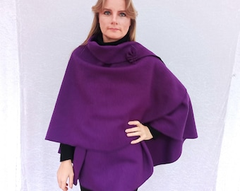 May include: A purple poncho with a high collar and a button detail. The poncho is made of a soft, warm fabric and is perfect for layering in the colder months.