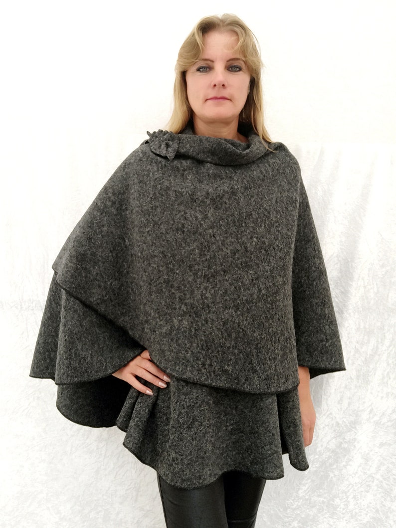 May include: A grey, double-layered poncho with a cowl neck and a ruffled hem.