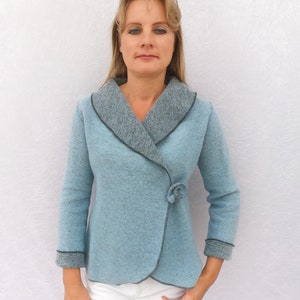 May include: A light blue wrap jacket with a dark gray collar and trim. The jacket has a single button closure and a slightly fitted silhouette.