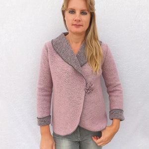May include: A pink wool jacket with a gray trim and a flower-shaped button. The jacket has a shawl collar and long sleeves.