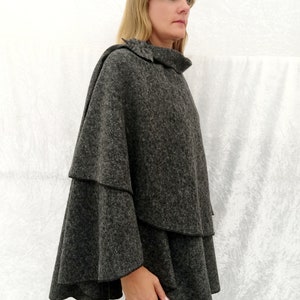 May include: A grey, tiered, poncho with a high neck and a ruffled hem.
