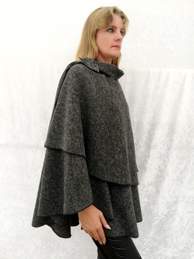 May include: A grey, tiered, poncho with a high neck and a ruffled hem.