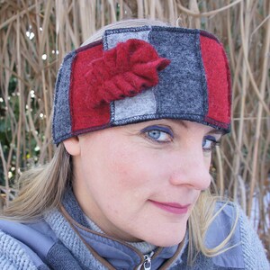 Könnte beinhalten: Ein Patchwork-Stirnband aus Filz in Rot, Grau und Schwarz, verziert mit einem roten Filzblatt. Das Stirnband ist so konzipiert, dass es die Ohren warm hält. Ein stilvolles Winteraccessoire.
