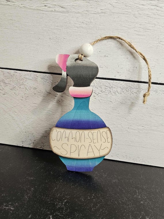 A laser-cut 'Common-Sense Spray' ornament that doubles as a deadpan editorial comment on whoever receives it — handmade snarky craft at its best.