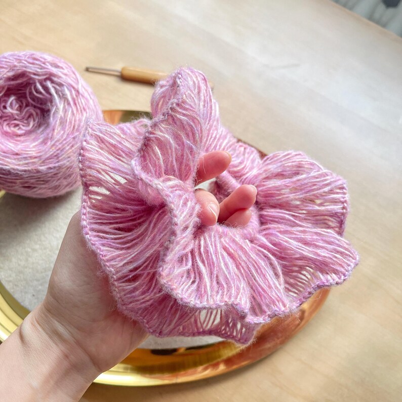 May include: A pink and white crocheted hair scrunchie with a ruffled design.