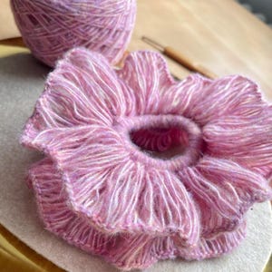 May include: A pink and white crocheted hair scrunchie with a ruffled design.