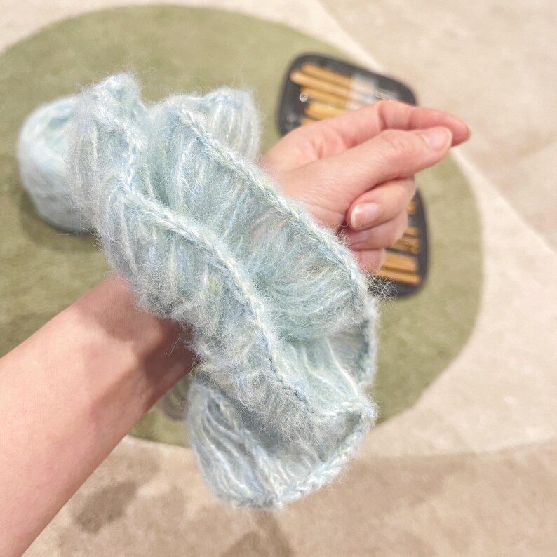 May include: A light blue and white fuzzy crocheted hair scrunchie.