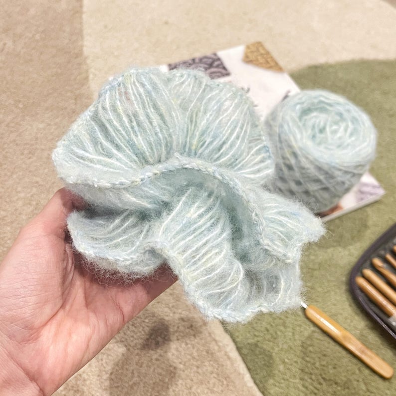 May include: A skein of light blue yarn with a subtle shimmer, perfect for knitting or crocheting. The yarn is soft and fluffy, and it has a delicate texture.