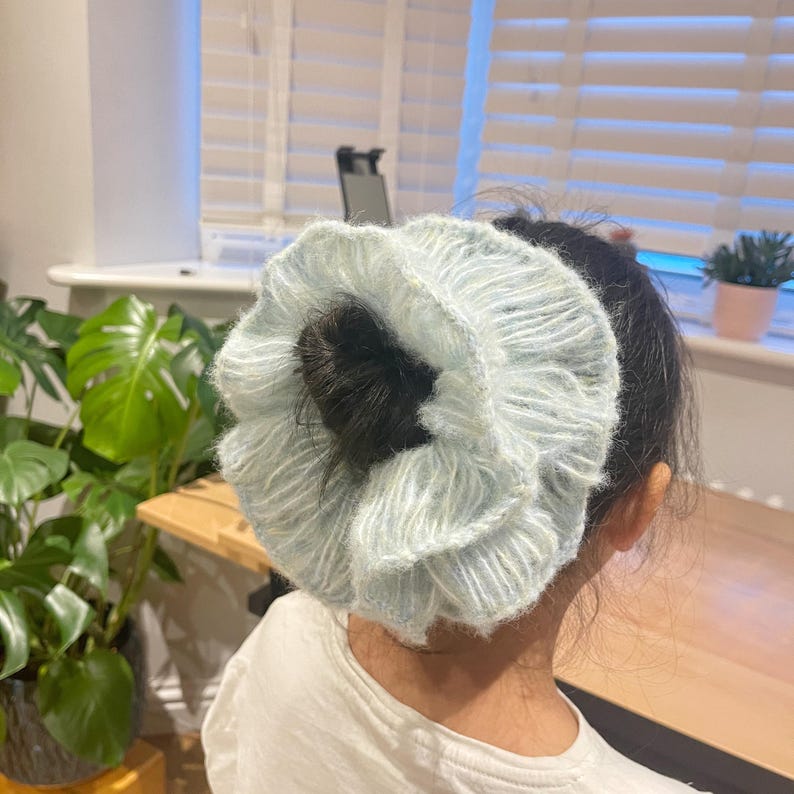 May include: A light blue fluffy scrunchie with a white stripe pattern. The scrunchie is tied around a ponytail.