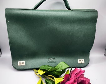 May include: A dark green leather briefcase with a silver handle and two silver clasps. The briefcase has the text "ADMR" embossed on the front.