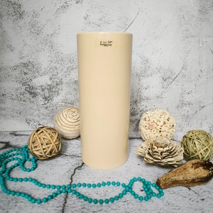 May include: A cream-colored ceramic vase with a label that reads "L'amour", surrounded by decorative balls and a turquoise beaded garland.