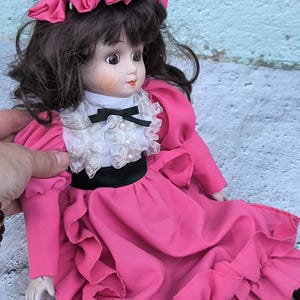 Vintage sitting doll with porcelain head, arms and legs, rag body, antique style collectible doll, brunette doll in bright pink dress