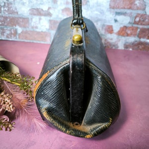 May include: A vintage black leather doctor's bag with a brass handle and clasp.
