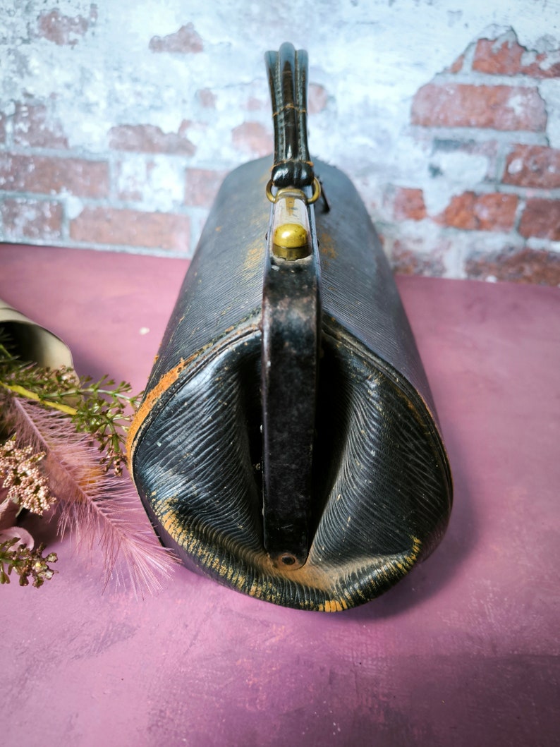 May include: A vintage black leather doctor's bag with a brass handle and clasp.