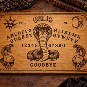 Könnte beinhalten: Ein rechteckiges Ouija-Brett aus Holz mit einer zentralen Kobra-Illustration, dem Alphabet, den Zahlen null bis neun sowie den Wörtern YES, NO und GOODBYE. Das Brett enthält zudem Gravuren eines Schädels mit Stern, einer Mondsichel und zwei Schädeln mit Schlangen.