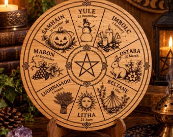 Op de afbeelding: Een ronde houten plaat met een lasergegraveerde jaarwielkalender. Het ontwerp bevat acht segmenten met illustraties en tekst voor Samhain, Yule, Imbolc, Ostara, Beltane, Litha, Lughnasadh en Mabon, met in het midden een pentagram.