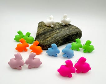 May include: A set of 10 colorful bunny rabbit stud earrings. The earrings are made of polymer clay and come in a variety of colors, including pink, blue, green, orange, and white.